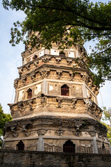 Fototapeta premium Tiger Hill Pagoda behind tree branches and brick wall in Suzhou, China, spring blue sky