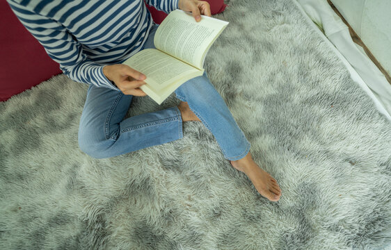 Woman reading a book on a cozy rug at home. Slow living, mindfulness, relaxation, digital detox, lifelong learning, mental wellness and peaceful everyday lifestyle. Mindful living, self education.