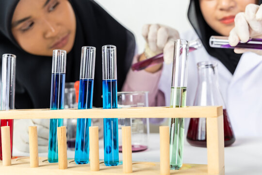 Two Muslim female scientists wearing hijab working in a chemistry laboratory with glassware and chemical solutions. Perfect for STEM education, research, science, healthcare, and biotechnology concept