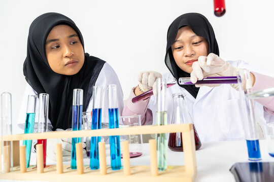 Two Muslim female scientists wearing hijab working in a chemistry laboratory with glassware and chemical solutions. Perfect for STEM education, research, science, healthcare, and biotechnology concept