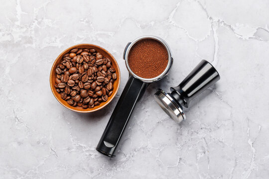 Coffee beans and espresso tools on white marble background