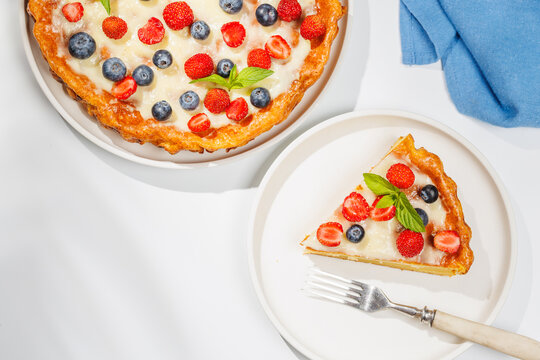 Slice of berry tart served on plate beside whole pie