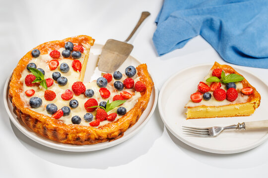 Whole berry tart with missing slice on white background