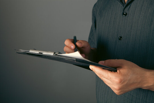 Businessman taking notes on a clipboard, closeup of hands.