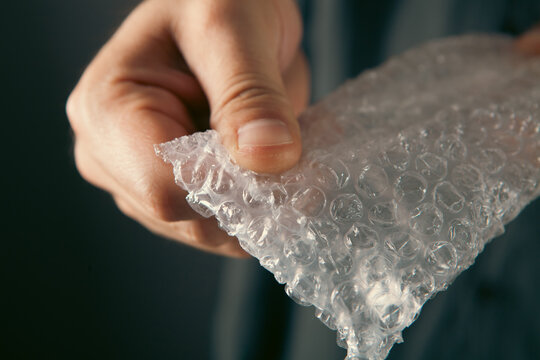 Man holding transparent plastic wrap in hand, closeup of photo.