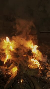 A mesmerizing bonfire burning brightly with fierce flames and thick smoke rising into the dark night