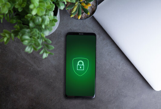 Smartphone with green security padlock icon on desk near laptop