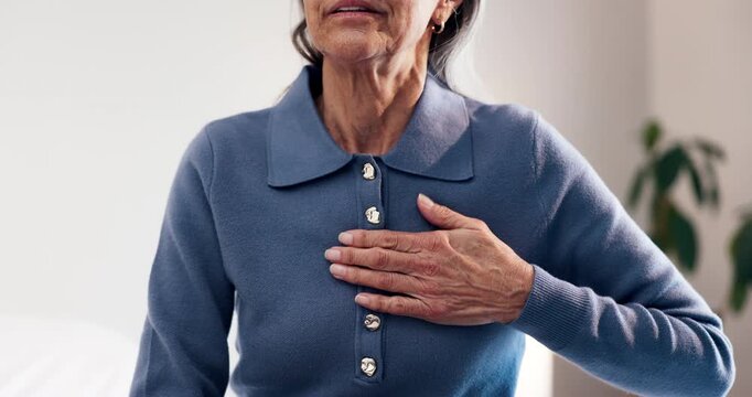 Chest pain, bed and hand of senior woman in home with discomfort, heartburn or asthma symptoms. Hypertension, medical emergency and elderly female person with cardiac arrest in bedroom of house