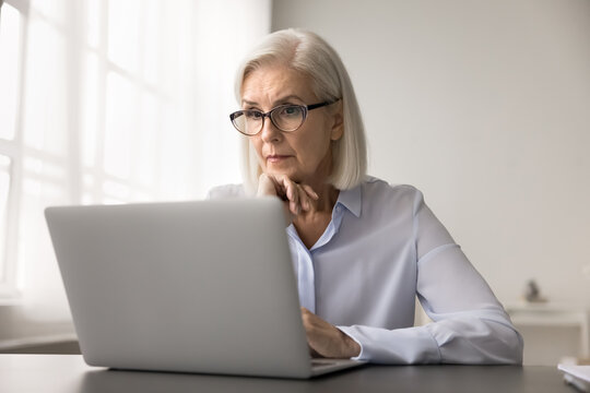 Worried senior female feel nervous stressed looking on laptop screen has doubts hesitate ponder on risky decision. Concerned businesswoman read email suspect fraud scam deal with too difficult problem