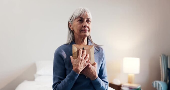 Senior, woman or thinking with picture frame in home for past memory, loss or mourning. Elderly, female person or widow with hug, photograph or moment of silence for grief, love or embrace in bedroom