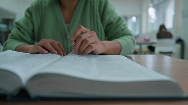Asian woman reading book at library.