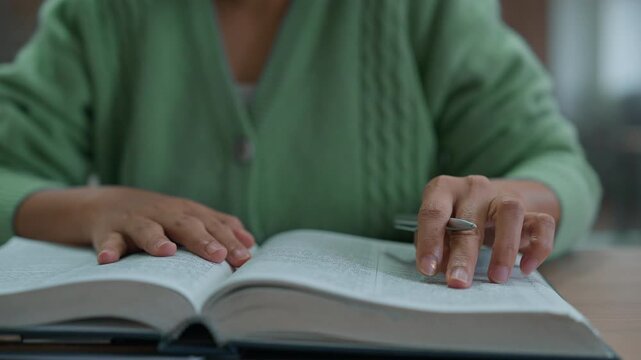 Asian woman reading book at library.