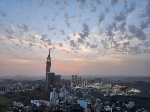 A magnificent panoramic view of Makkah captured from Jabal Khandamah during sunset. Warm golden light bathes the city's skyline