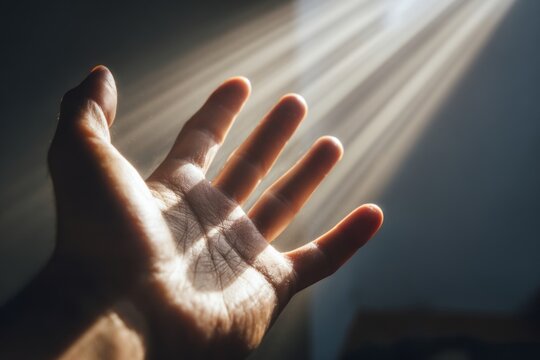 Open hand reaching towards sunlight streaming through a window, showcasing intricate details of skin texture and light reflections. sensory summer concept