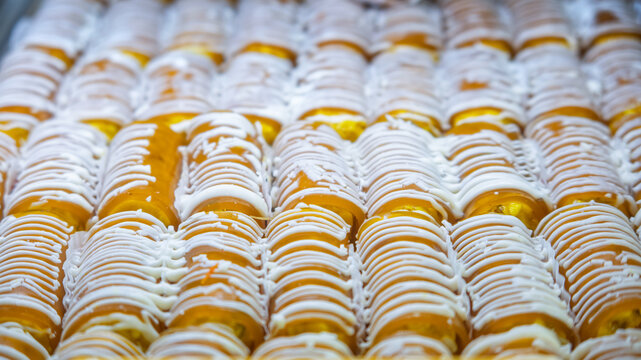Golden pastries drizzling with white icing in rows