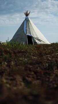 Conical Canvas Tent on Open Tundra Under Cloudy Sky