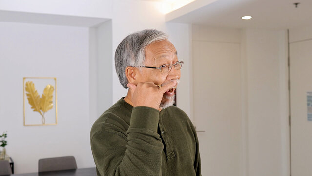 Senior Asian Man Gesturing Phone Call While Smiling in Modern Home