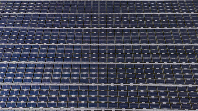 An aerial view shows workers cleaning solar panels in a large body of water.