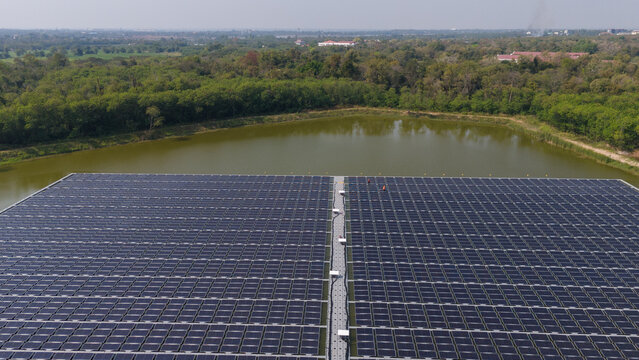 An aerial view shows workers cleaning solar panels in a large body of water.