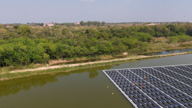 An aerial view shows workers cleaning solar panels in a large body of water.