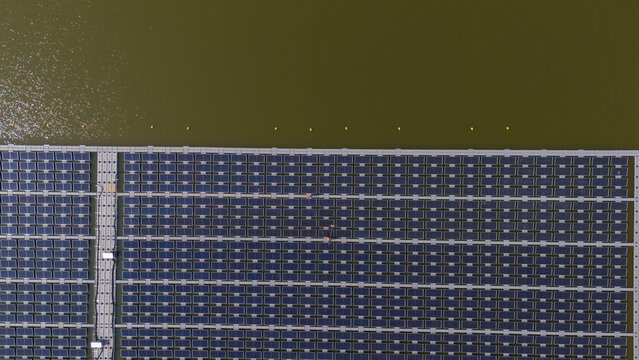 An aerial view shows workers cleaning solar panels in a large body of water.