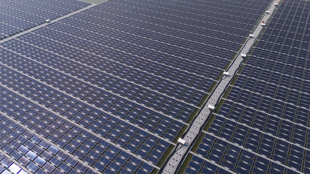 An aerial view shows workers cleaning solar panels in a large body of water.