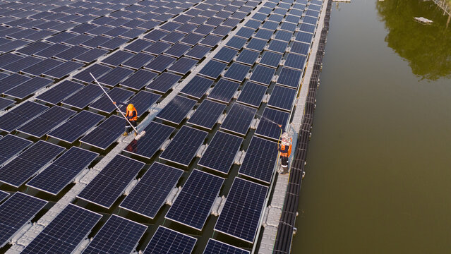 An aerial view shows workers cleaning solar panels in a large body of water.