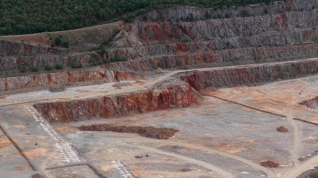 An aerial perspective shows a large open pit quarry with exposed rock strata, illustrating industrial resource extraction and geological formations.