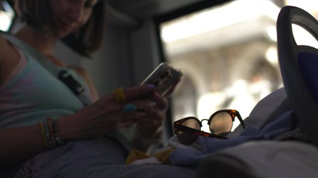 The young girl keeps her smartphone on the bus, carries a backpack and maintains a neutral facial expression during her daily commute, the girl on the bus. 