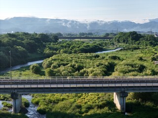 Fototapeta premium Bridge spans calm river through green forested valley