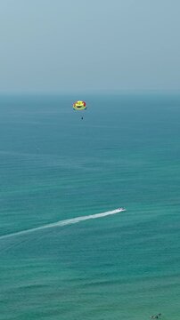 Aerial view of parasailing over the sea in Da Nang, Vietnam, showing a parasail above the blue water - drone, vertical shot