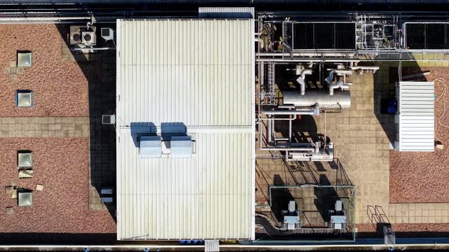 Top-down vertical aerial view looking directly down at a complex layout of industrial HVAC chiller units, extractor vents, and piping networks on a factory roof.