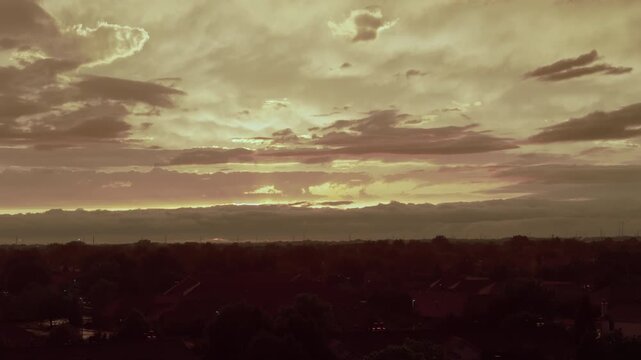 Aerial shoot of Dramatic golden storm clouds illuminated by the setting sun above a suburban neighborhood after heavy rain. 