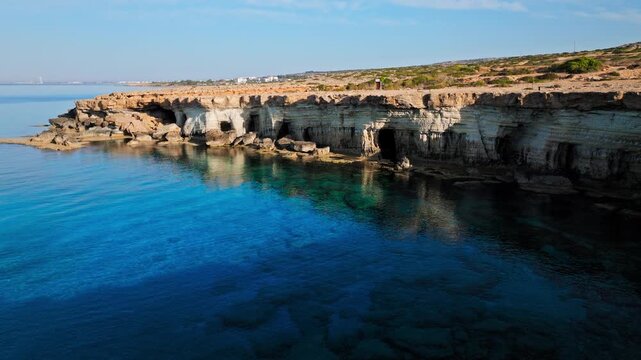 Drone view of the Cape Cavo Greco Sea Caves shoreline. The blue sea and layered limestone coast create a scenic Cyprus travel landscape.