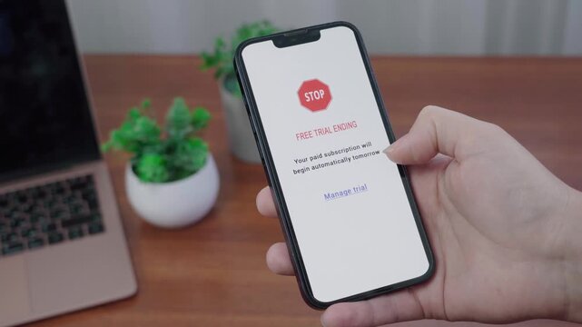 Person holds a phone showing an AI subscription message that a free trial is ending and paid billing will start automatically.