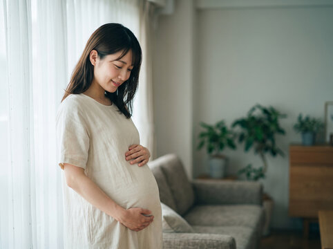 両手で膨らんだお腹を愛おしそうに撫でるマタニティ姿の女性