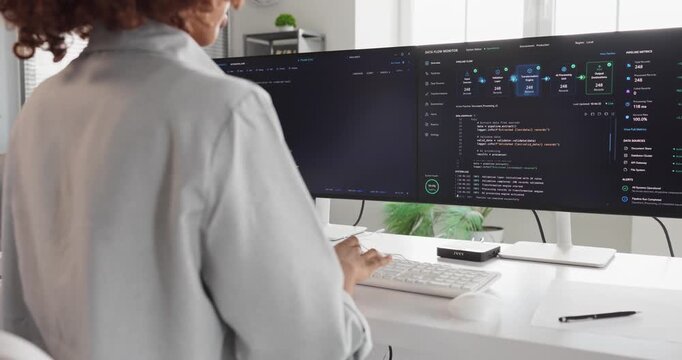 Developer programmer coding software code in office. Engineer at dual monitors reviews commits and debugs in a bright workspace using agile technology. Strong collaboration and teamwork concept.