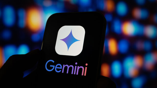 A close up of a hand holding an iphone with the gemini logo on the screen against a bokeh background.