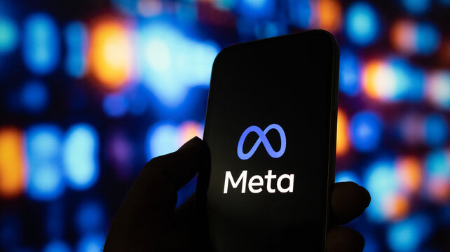 A close up shot of human hand holding smartphone with meta platforms logo on black screen.