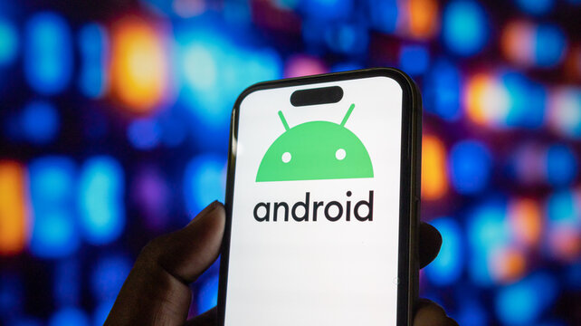 Person holding smartphone showing green android logo against glowing blurred blue light background.