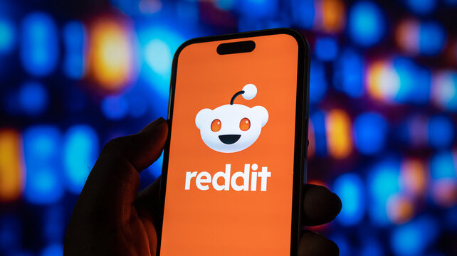 Person holding phone displaying reddit logo, popular social news aggregation and discussion website.