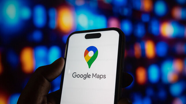 Person holding iphone 15 pro max with google maps logo on screen against blurred vibrant background.