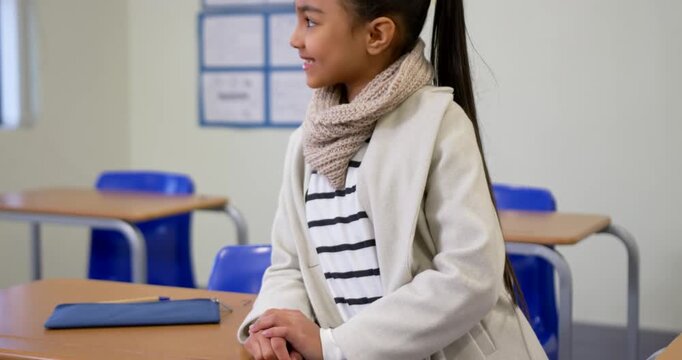 Child preteen girl noticing motion right, turning to camera, sitting at classroom desk pencil case