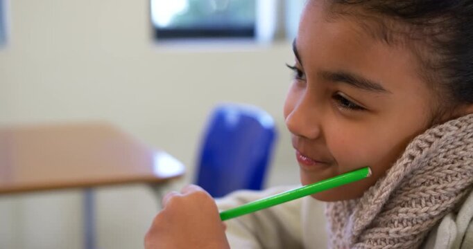 African American child holding pencil on cheek shifting reacting offscreen in class, copy space