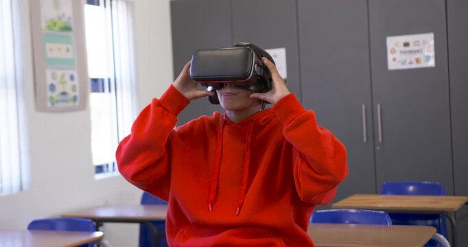 African American teen in red hoodie in VR demo at school reaching adjusting and inspecting headset