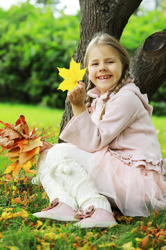 Joyful Girl in Autumn Park Holding Colorful Leaves and Smiling