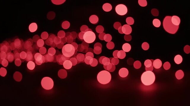 Abstract background of red bokeh light circles glowing in the dark with soft out of focus light orbs creating a romantic and festive celebratory mood for holiday or party themes