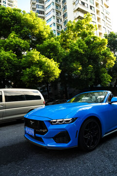 Shanghai, China, Asia - July 11, 2027: A blue Ford Mustang convertible is driving on a street in downtown Shanghai.