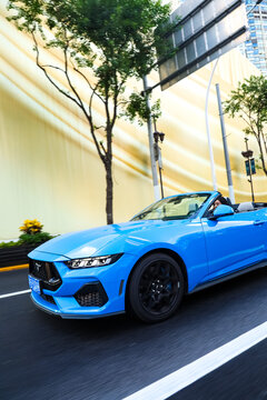 Shanghai, China, Asia - July 11, 2027: A blue Ford Mustang convertible is driving on a street in downtown Shanghai.