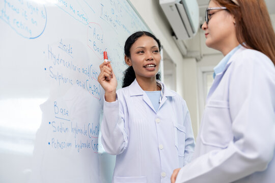 African American scientist writing on whiteboard in laboratory